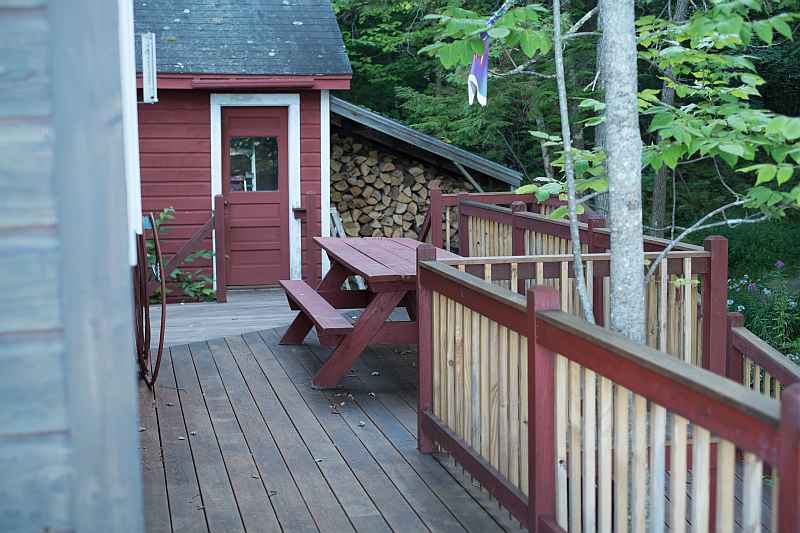 Side deck showing picnic table, shed, and firewood